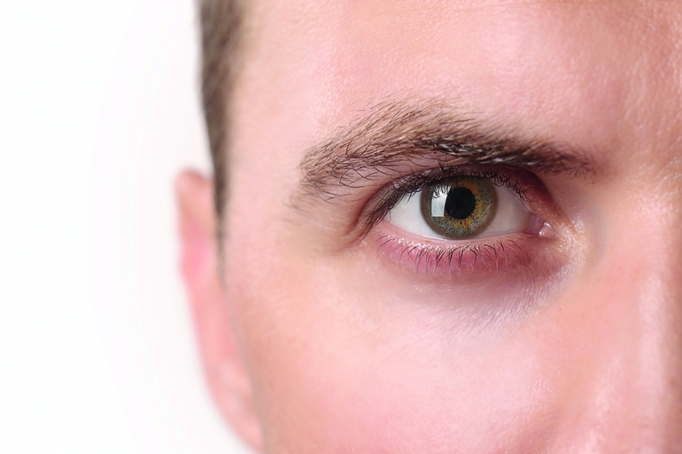 Close up view of a green man's eye looking at camera